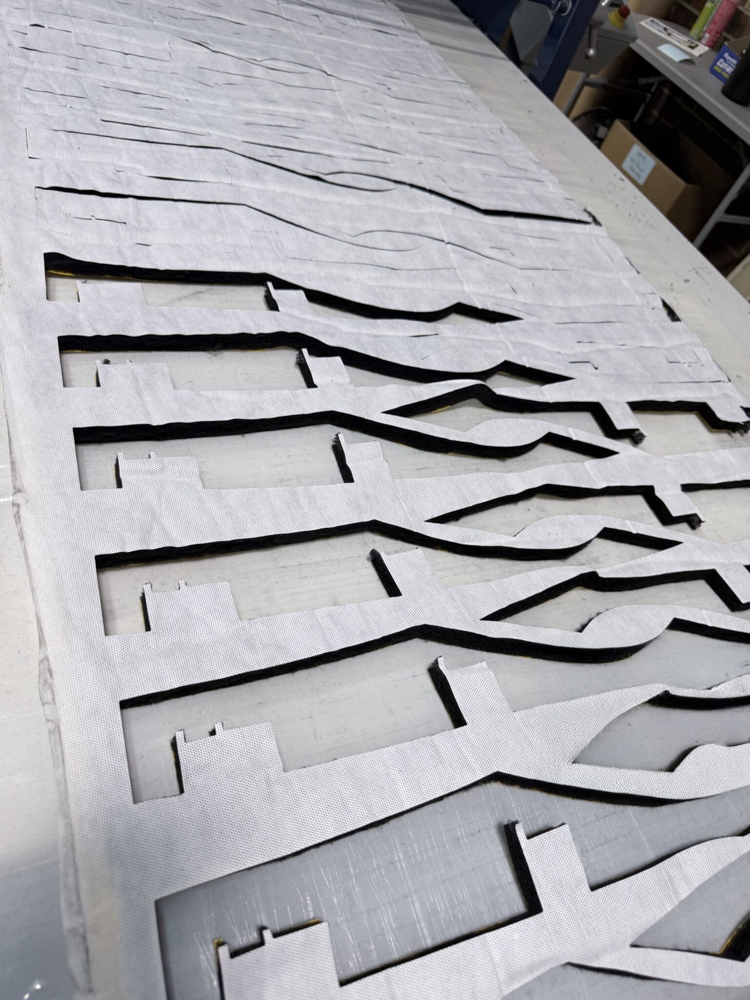 Cut fabric pieces are arranged in a wavy pattern on a table, possibly for a sewing project or textile design.