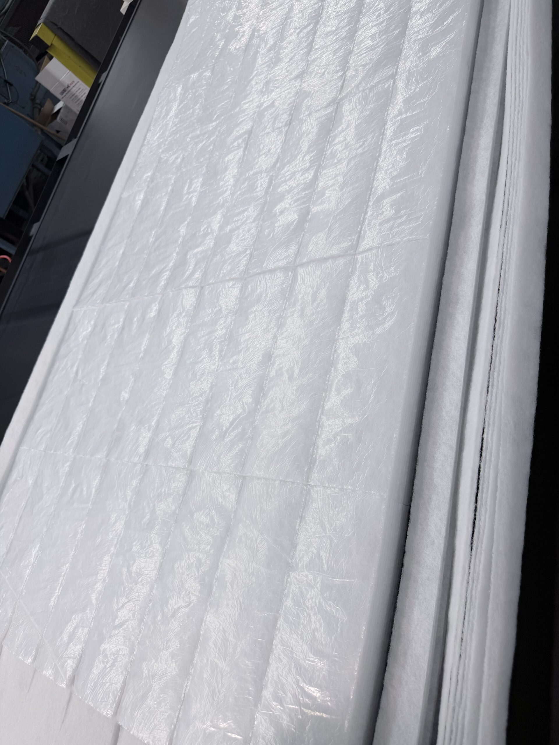 Translucent sheets of white material stacked neatly, likely for packaging or textile production, displayed on a black surface.