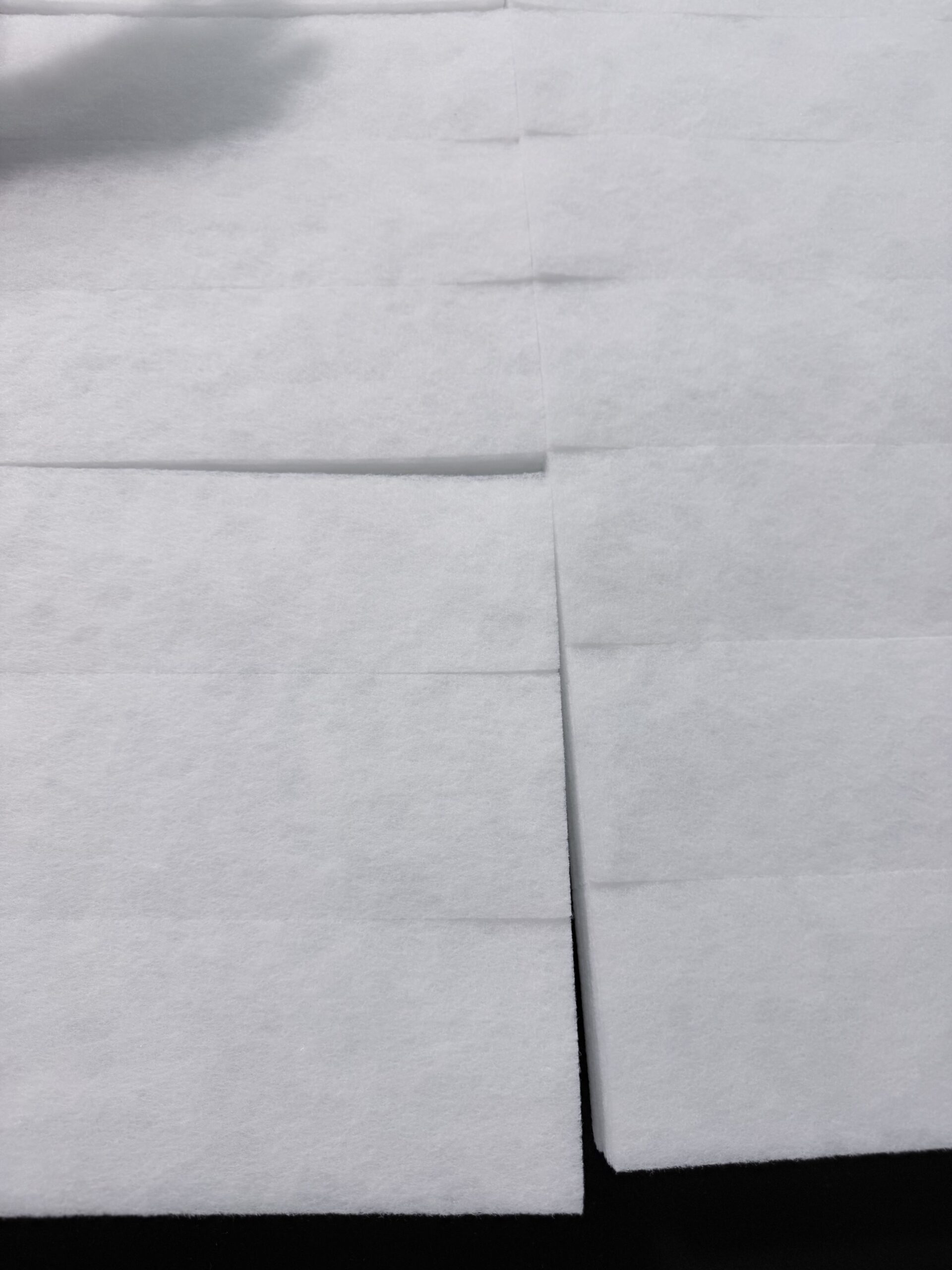 White felt sheets are arranged on a dark surface, showing neatly folded sections.